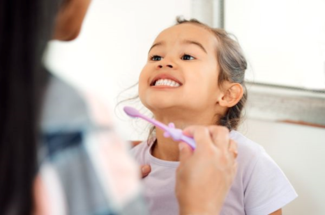child smiling in front of parent holding toothbrush
