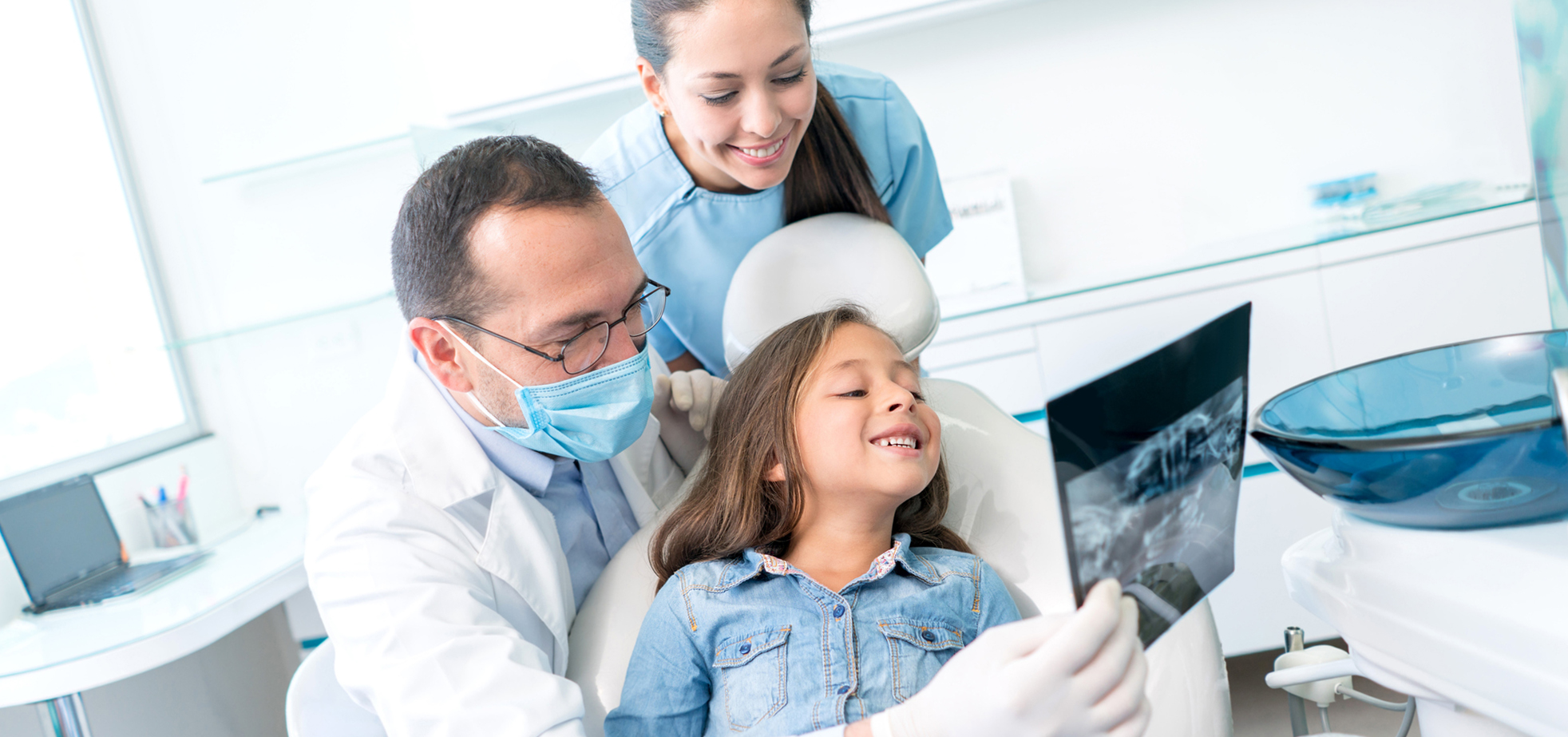 dental professional holding up an xray to a child in the dental chair